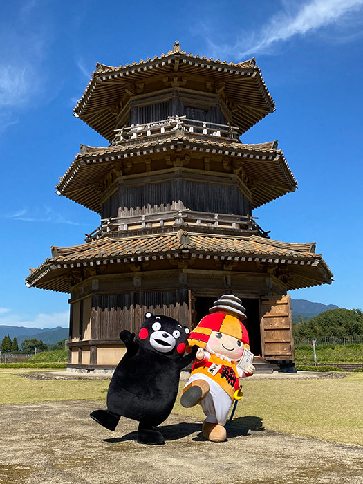 くまモンところう君 後ろは鞠智城のシンボル・八角形鼓楼(ころう)