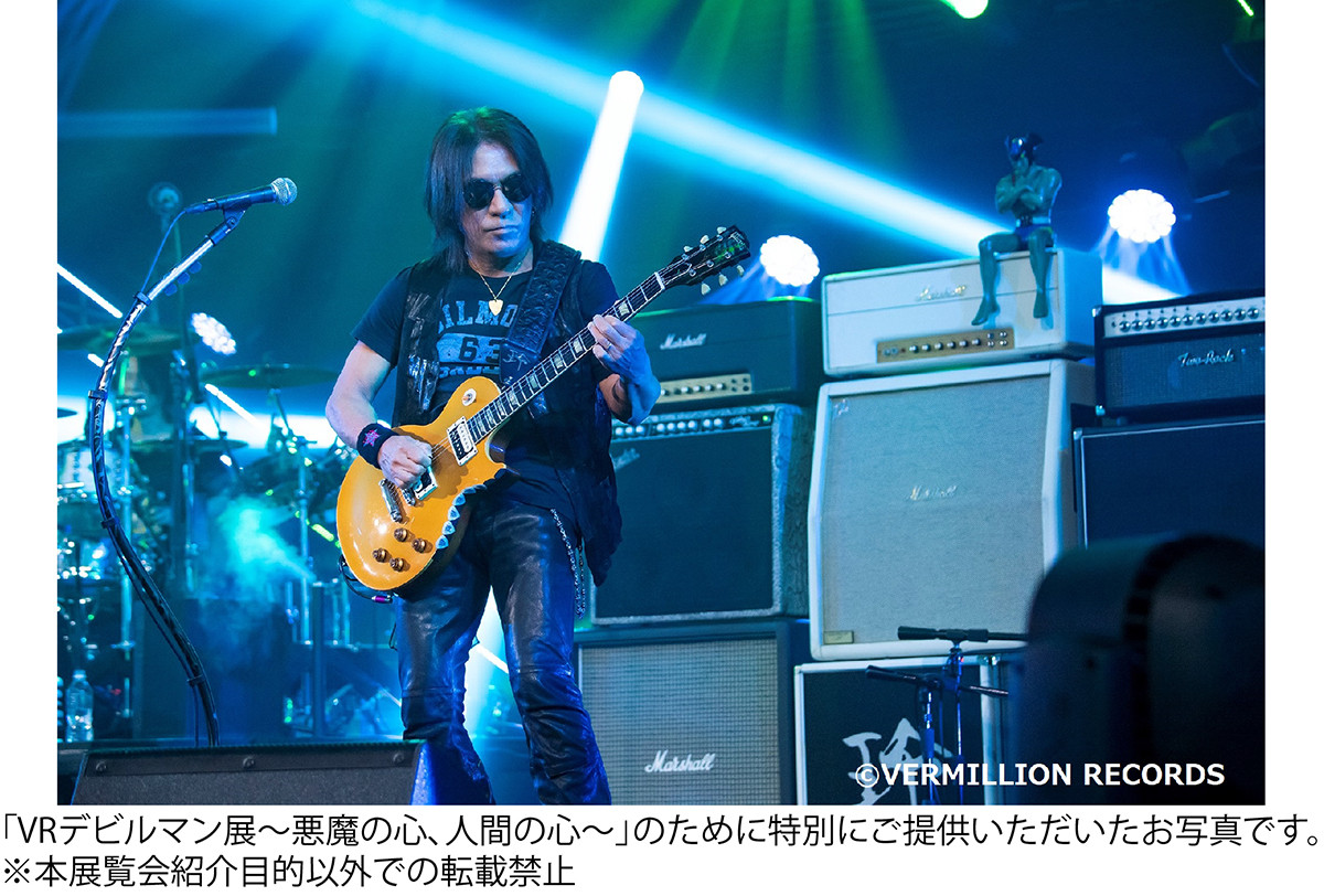 背後に鎮座するデビルマンに見守られながら演奏中の松本孝弘氏(B’z)