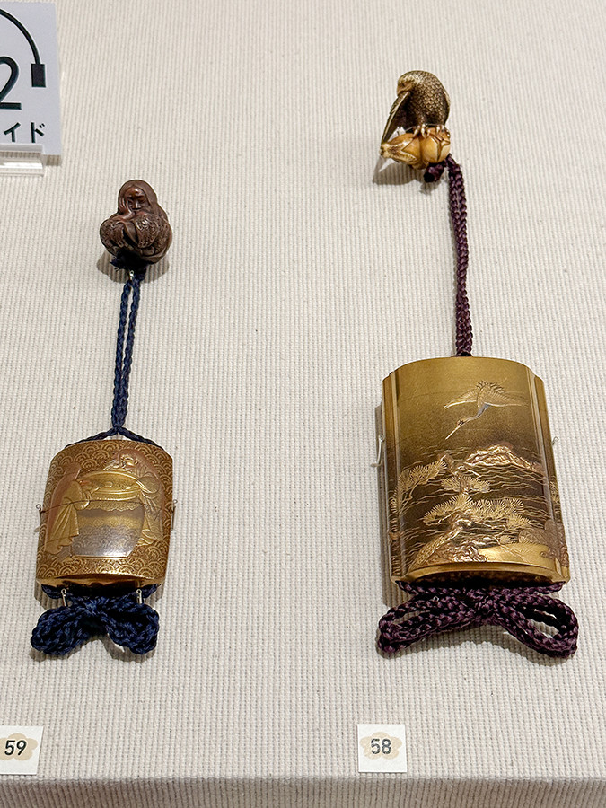 静嘉堂文庫美術館「初春を祝う ― 七福うさぎがやってくる!」会場より (左から)印籠:2代豊川楊渓《猩々蒔絵印籠・木彫根付 眠り猩々》江戸~明治時代・19世紀 / 印籠:山本光利《浜松に鶴蒔絵印籠・象牙彫根付 鷹に茄子》江戸~明治時代・19世紀