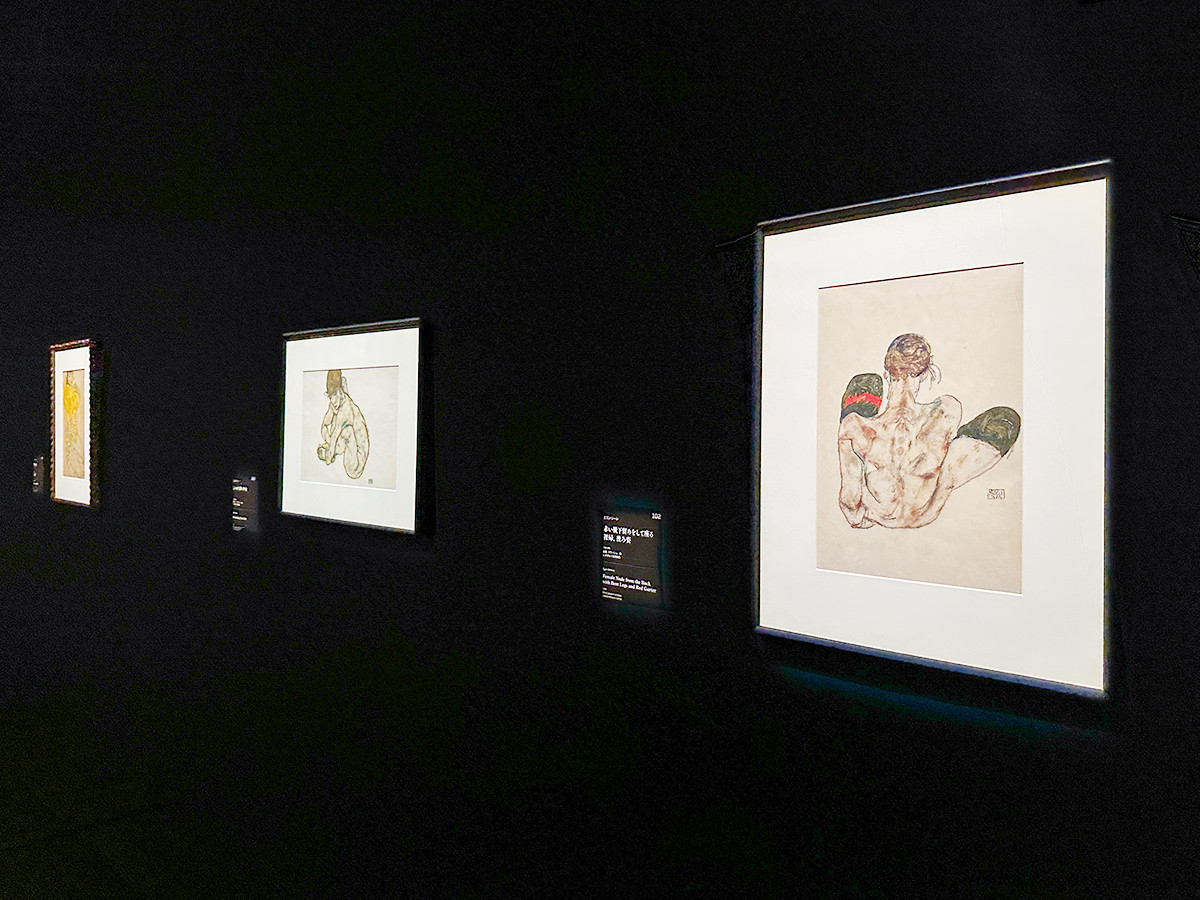 東京都美術館「レオポルド美術館 エゴン・シーレ展 ウィーンが生んだ若き天才」会場より　（右）エゴン・シーレ《赤い靴下留めをして座る裸婦、後ろ姿》1914年 レオポルド美術館