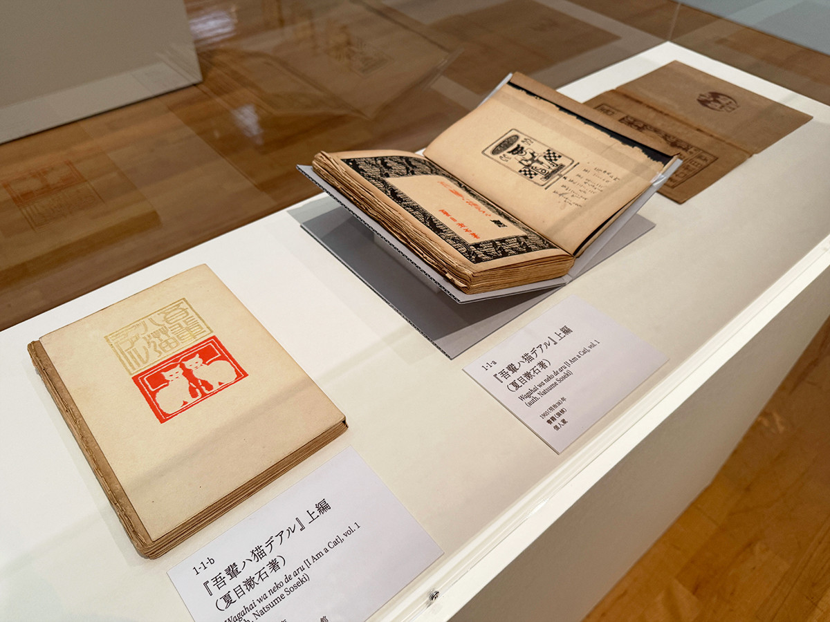 府中市美術館「橋口五葉のデザイン世界」会場より (左手前から)『吾輩八猫デアル』上編(夏目漱石著)1905(明治38)年 新宿区立漱石山房記念館 / 『吾輩ハ猫デアル』上編(夏目漱石著)1905(明治38)年 個人蔵