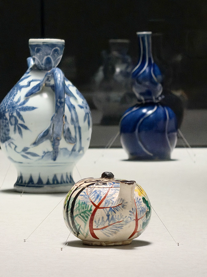 サントリー美術館「眼のごちそう 食器」会場より (手前)《色絵春草文汁次》尾形乾山 江戸時代 18世紀 サントリー美術館 / (中)《染付桃形酒入》景徳鎮窯 明時代 17世紀 個人蔵